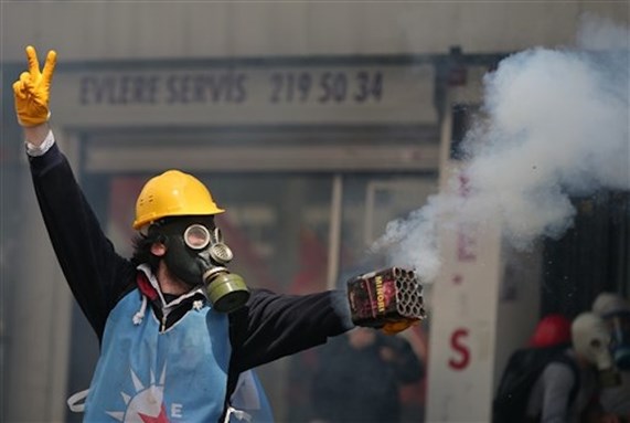 [A protester stands as riot police use water cannons and teargas to disperse thousands of people trying to reach Taksim Square to celebrate May Day in Istanbul, 1 May 2014. (AP Photo/Emrah Gurel)]