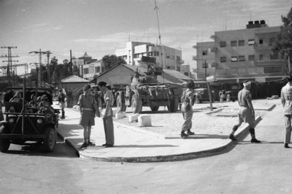 [Following the disturbances in Tel Aviv in November 1945, a Palestinian constable acts as an interpreter for the officer in charge of a British Army patrol on the streets and warns people against remaining in the area. Image by No 1 Army Film & Photographic Unit, Meek F (Sgt)]