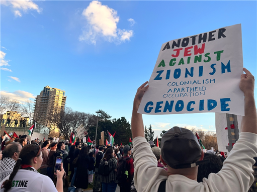 A person holding sign reading "Another Jew Against Zionism, Colonialism, Apartheid, Occupation, Genocide" at a protest. Photo by Jenari via Shutterstock.