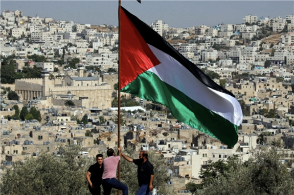 Demonstrators place a Palestinian flag during a protest against Israeli Prime Minister Benjamin Netanyahu's visit to Hebron, in the occupied West Bank, September 4, 2019 via Reuters by Mussa Qawasma