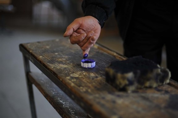 [A man dips his finger in ink after casting a vote at a polling station during a parliamentary election in Cairo. Photo credit Washington Post.]