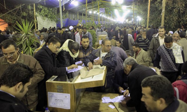 [Egyptian election officials count votes in front of a ballot box at a counting center during election runoffs, Thursday 22 December 2011. Image from AP]