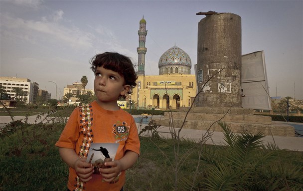 [Three-year-old Hussein in Firdos Square Baghdad holding a photo of the site taken by Jerome Delay (AP) of US forces and Iraqis on 9 April 2003 pulling down Saddam Hussein`s statue. Image by Maya Alleruzzo-AP] 