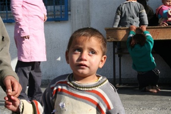 [A boy outside his school after a bombing in Gaza, 2009. Image by Al Jazeera English via Wikimedia Commons.] 