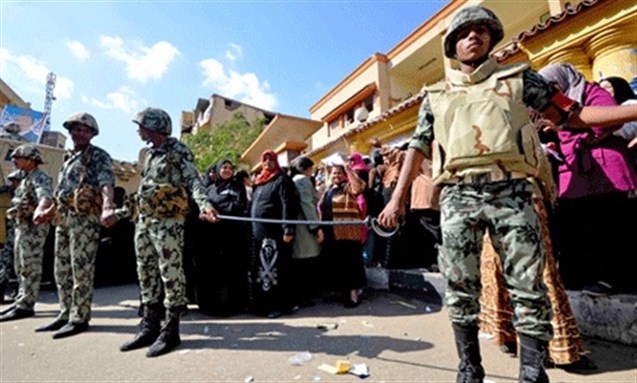[Egyptian Army soldiers stand guard as voters wait outside a polling station in Luxor. Image from AP]