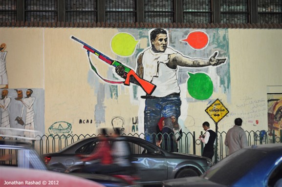 [Mural for prisoned fighter `Sambo`, on Mohamed Mahmoud street. Sambo is serving a military prison sentence after confiscating a shot-gun from police forces during clashes between them and families of martyrs of the revolution on 28 June 2011. Photo by Jonathan Rashad]