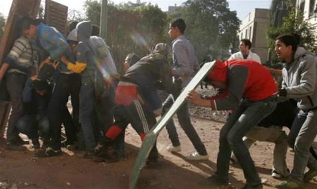 [Egyptian protesters protect themselves behind makeshift shields during clashes with army troops near Tahrir Square in Cairo, Egypt. Image from A.P.]