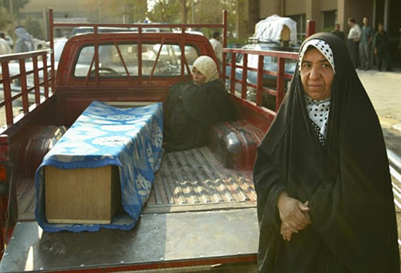 [Relatives wait with the coffin of a girl who died of cancer, outside Saddam Medical City in central Baghdad, 17 April 2003. AP Photo/Lefteris Pitarakis.]