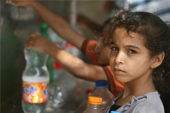 Children in Gaza gather water from one of a few remaining taps following the conflict in 2014. More than 90% of the water in Gaza is unfit to drink and its aquifer suffers from pollution and salinisation. Credit: Mohammed Al Baba/Oxfam