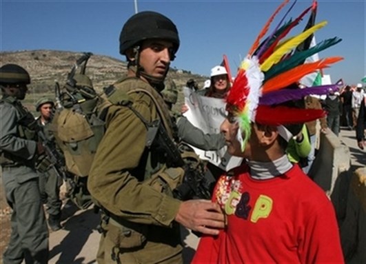 [An Israeli soldier grabs a Palestinian boy, dressed as a Native American during a protest in Nablus. AP Photo/Nasser Ishtayeh]