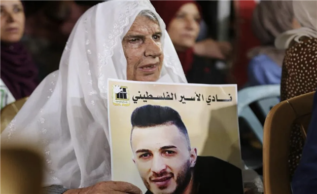 Palestinians hold placards during a protest in solidarity with prisoner in Israeli jails Ghadanfar Abu Atwan, in the West Bank city of Hebron on July 4, 2021 via Apaimages