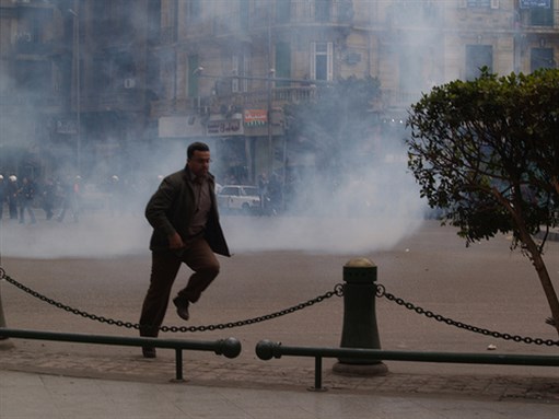 [27 January 2011, protester running from tear gas fired by the security forces. Image originally posted to Flickr by Ramy Raoof]