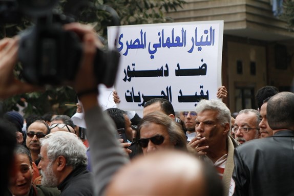 [A banner held by an Egyptian Secular Current member reads: \"The Egyptian Secular Current is against a constitution that limits freedoms\". Image by Sarah Carr.]