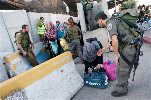 [Israeli soldiers check Palestinian women and children at the Bethlehem checkpoint on the last Friday of Ramadan, West Bank, August 17, 2012: Image from www.shutterstockcom]