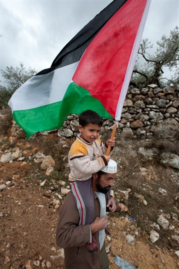 [An unidentified boy carries a Palestinian flag and rides on his father`s shoulders protesting the Israeli separation wall in Al-Walaja, West Bank on Nov 18, 2011: Image from www.shutterstockcom]