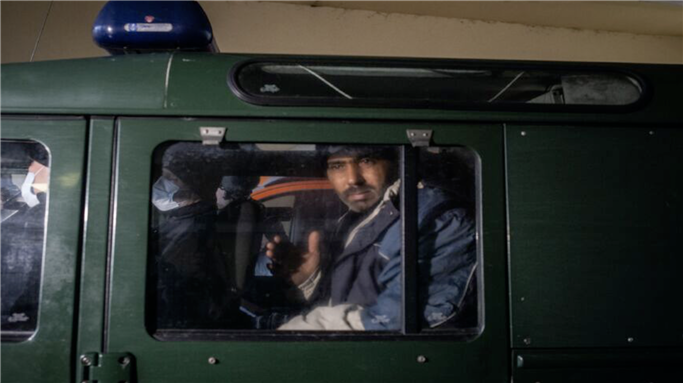 Syrian migrant Masour Nassar, 42, from Aleppo, who has applied for asylum in Poland is taken by Polish border guards out of the Rafala Czerwiakowskiego Hospital Emergency ward of the district hospital on Nov. 19, 2021, in Bielsk Podlask, Poland. [Maciej Moskwa/Getty Images]