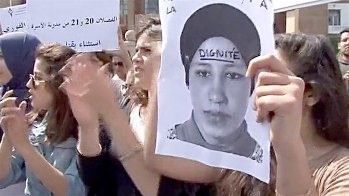 [An image of Amina Filali is held with the word \