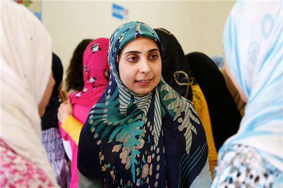 A Lebanese woman talks to two Syrian refugee girls about gender-based violence. Photo by DFID via Wikimedia Commons.
